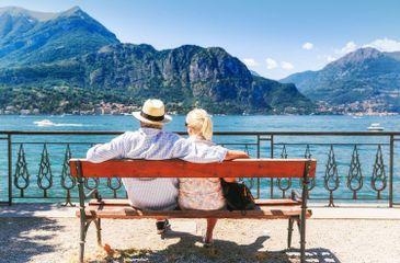 Lake Como, village Bellagio, Italy. Senior couple weekend getaway having rest on the bench by spectacular lake Como in Italy. Sunny day scenery. (1).jpg